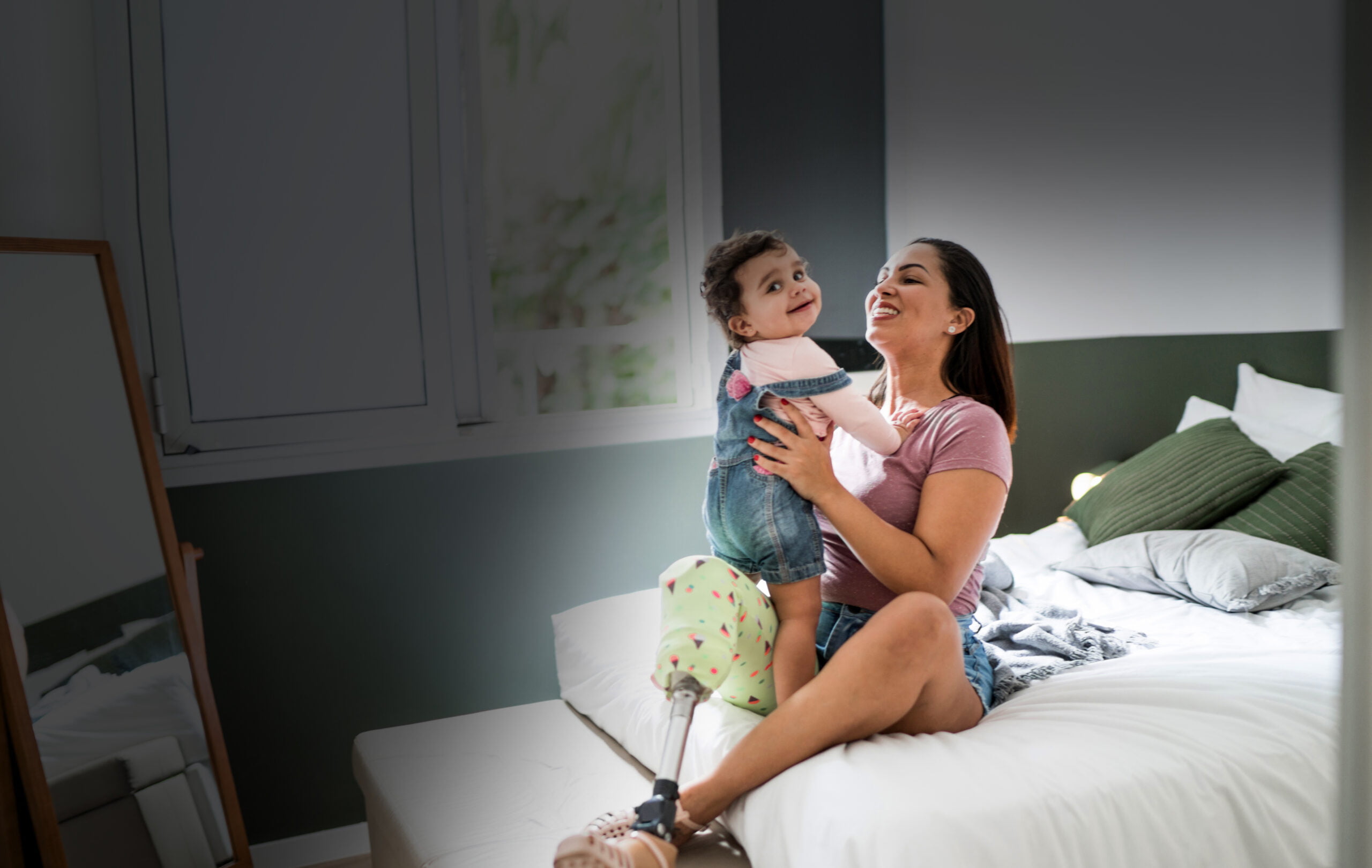 Mother with disability sitting on a bed playing with baby girl
