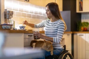 Woman in wheelchair in kitchen NDIS modified home with cat