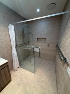 Photo of a renovated bathroom by Restore Home Modifications. The shower features a grab rail and a shower seat.